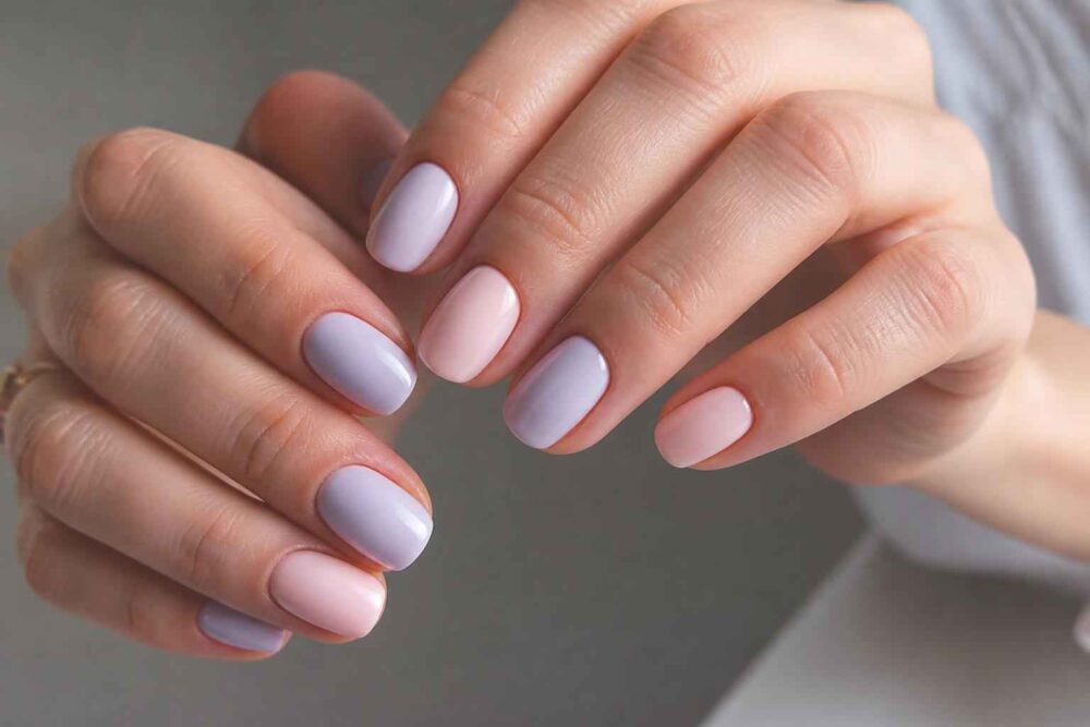 Dłonie z pastelowym manicure w odcieniach różu i lila unerquicklich