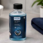 Butelka płynu Philips Jet Clean stojąca na łazienkowym blacie obok ręcznika i umywalki